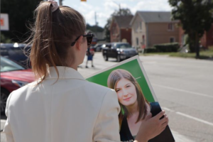 (over-the-shoulder shot of Karleigh Csordas holding an election sign)